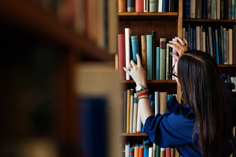 Rear view of woman searching book in library