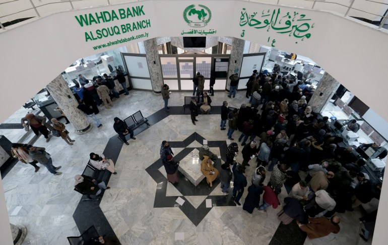 People crowd in front of a counter at Wahda Bank to complete the procedures of credit cards in Benghazi