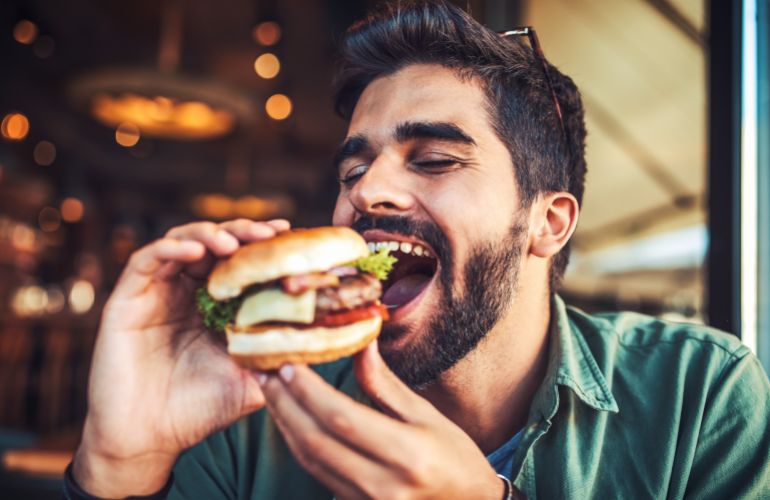 Good appetite. Young man sitting in a cafe and enjoying in breakfast. Food, lifestyle concept